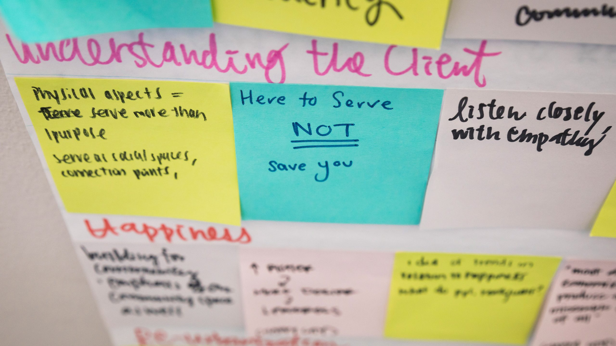 Post-it notes on the walls of a Cal Poly architecture studio saying "Here to serve you, not save you." Photo by Joe Johnston.