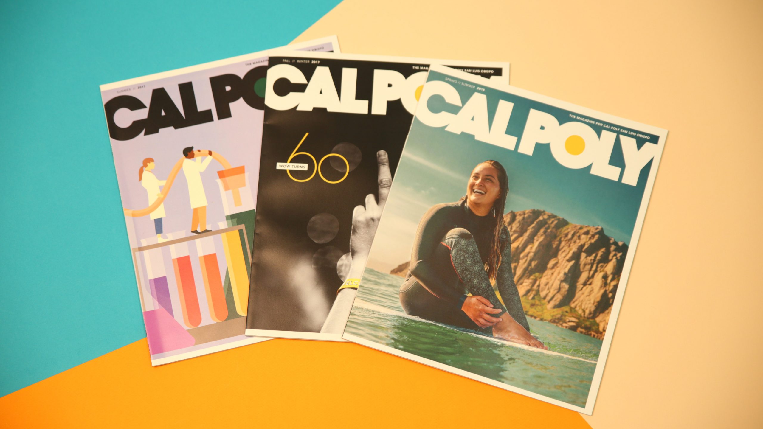 Three issues of Cal Poly Magazine arranges on an orange, blue and creme background.