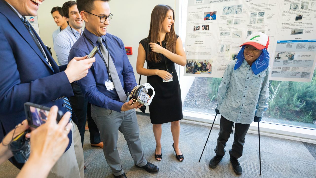 Engineering students present a prosthetic hand to Julian Reynoso in the Advanced Technologies Laboratory