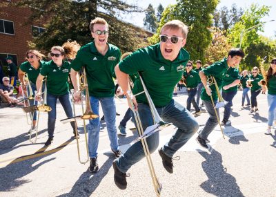 Band members jump while holding their instruments at the Open House Parade.
