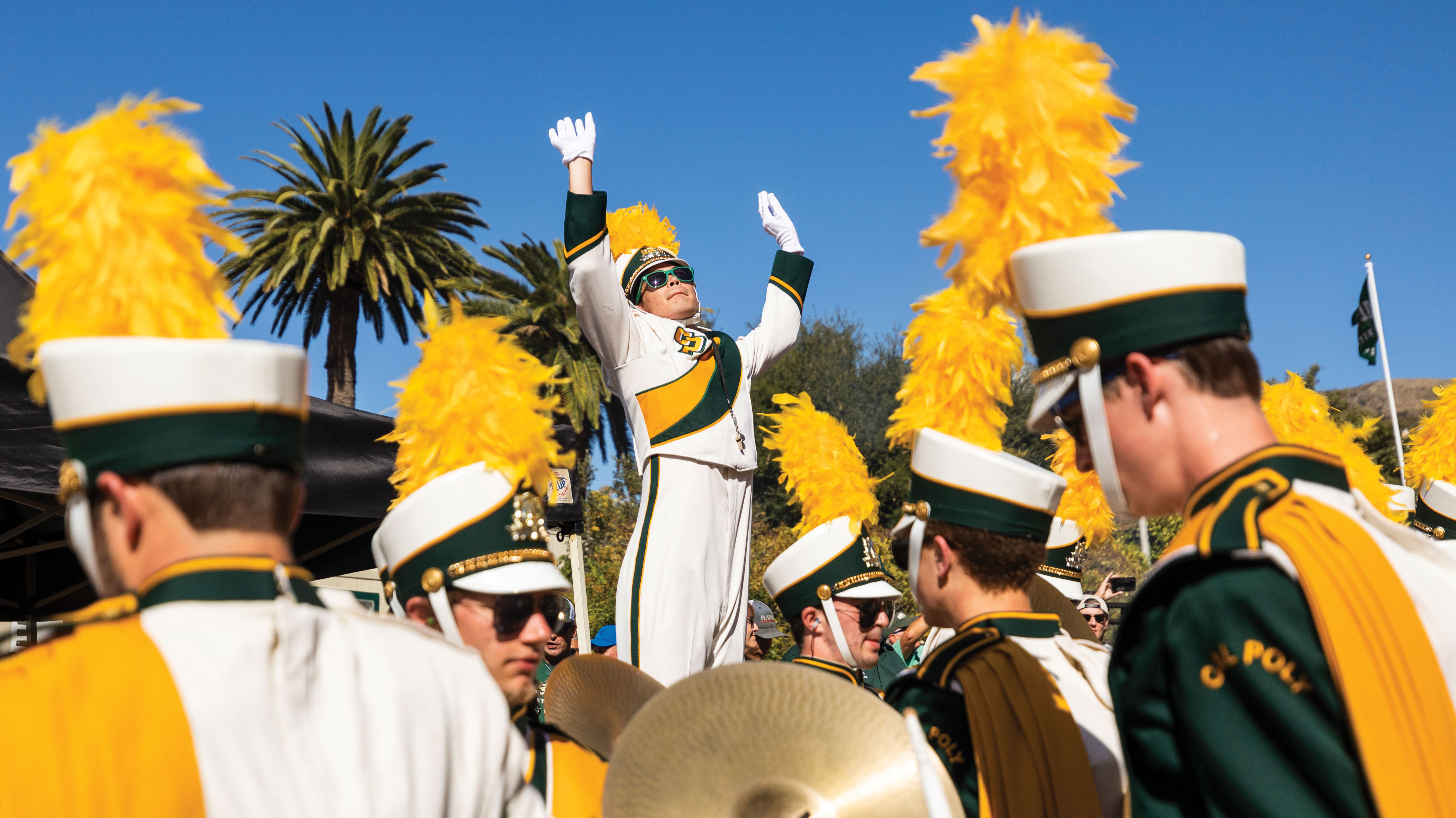 A drum major conducts marching band members with his arms up on Cal Poly's campus