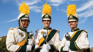Drum majors Ben Howard, Kent Giese and Kai Quizon hold their maces before a home football game