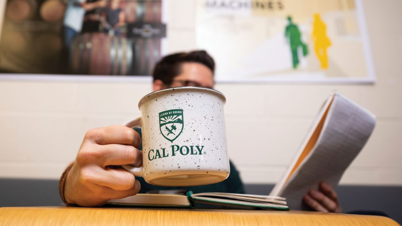 Cal Poly Magazine Editor Larry Peña holds a coffee cup in his office.