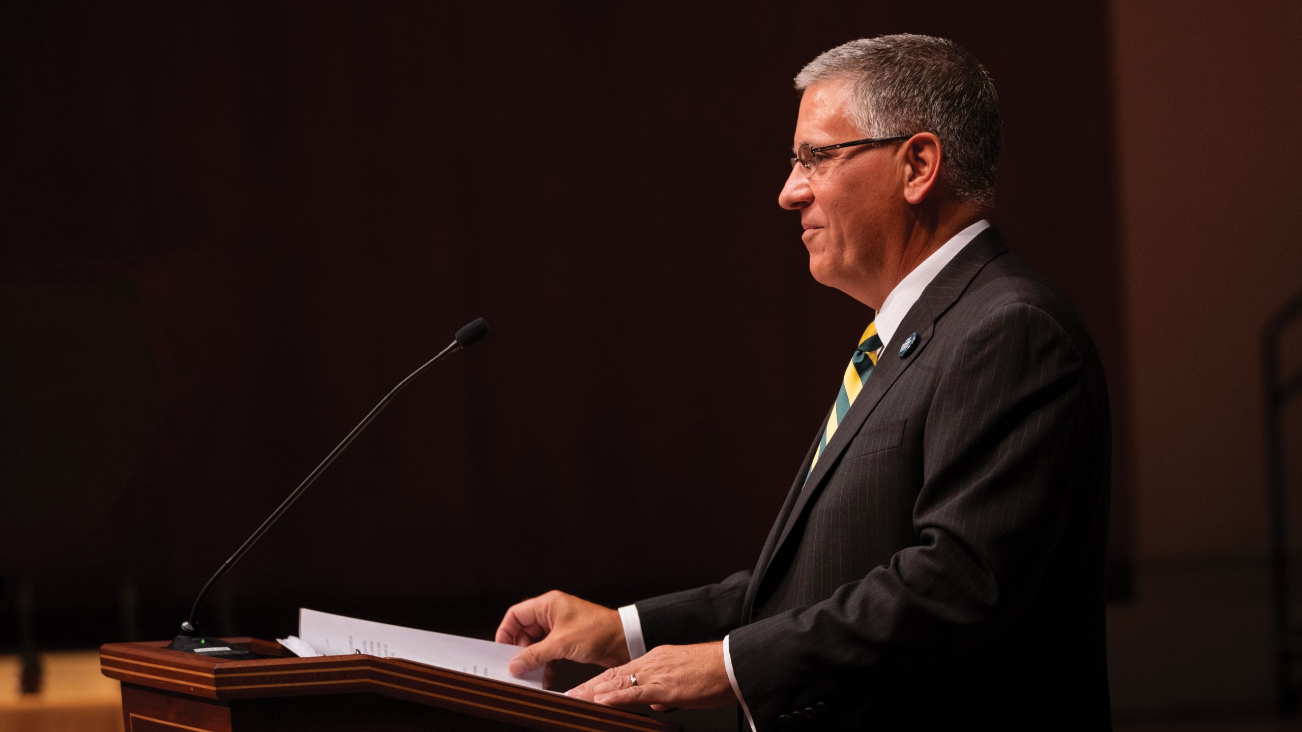 President Armstrong smiles at the podium in the Performing Arts Center