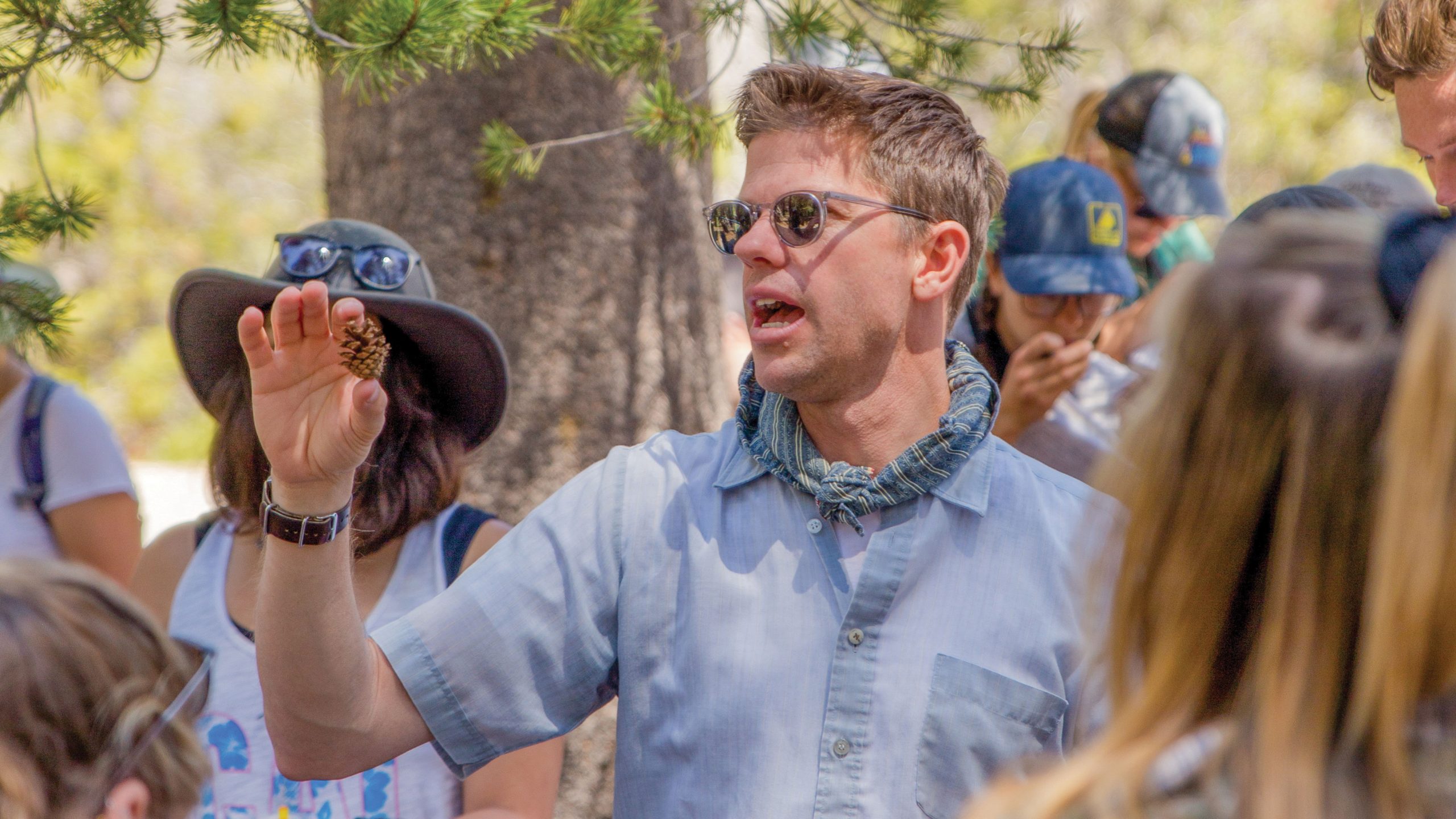 Biology Professor Matt Ritter holds a pinecone while lecturing students during a field trip.