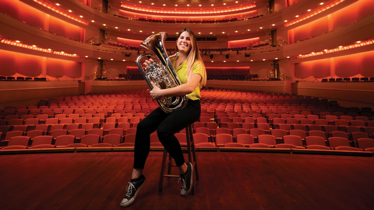 Architecture student Emma Gracyk smiles on the Performing Arts Center stage with her euphonium.