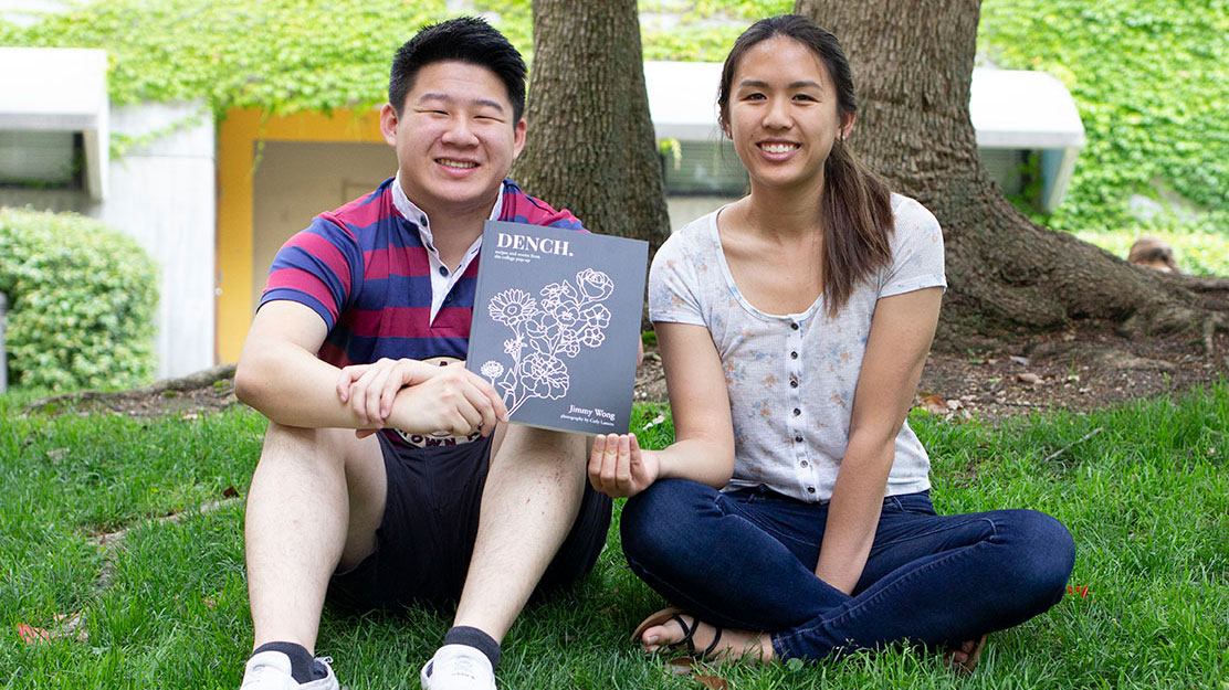 Student chef Jimmy Wong and designer Carly Lamera hold a copy of the DENCH cookbook they created together