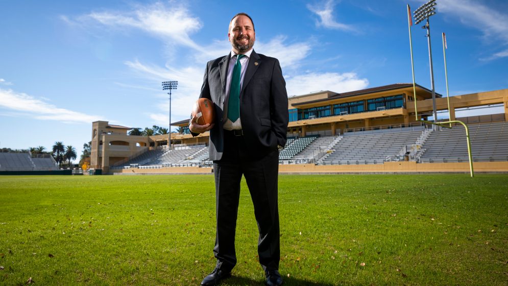 Football head coach Beau Baldwin holds a football in Spanos Stadium