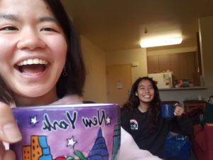 Two young women smile while holding up teacups