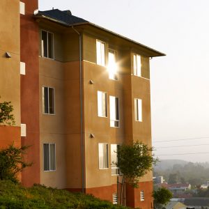 Sunlight reflects off the windows of a yellow and tan apartment building