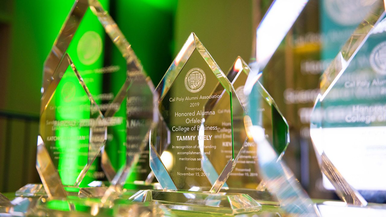 A group of clear glass awards on a table, backlit with green and white light