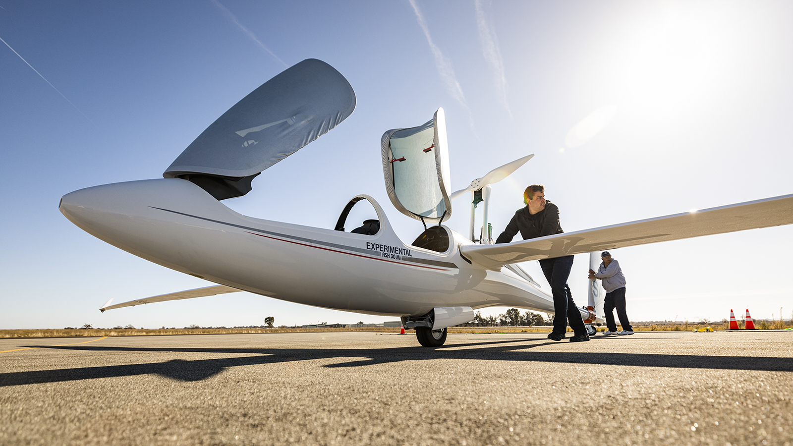 Professor Paulo Iscold pushes a lightweight experimental aircraft onto a tarmac for a test flight.
