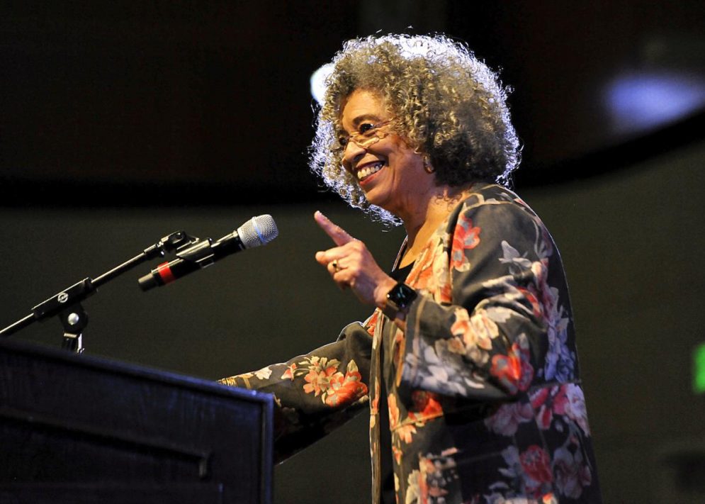 Angela Davis gestures while speaking into a microphone at a Cal Poly event.