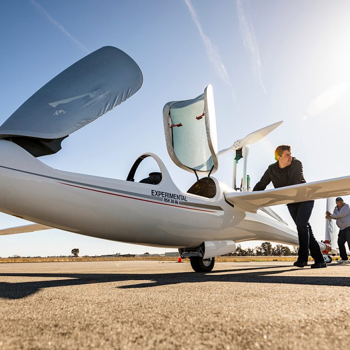 Two men push a glider across the tarmac