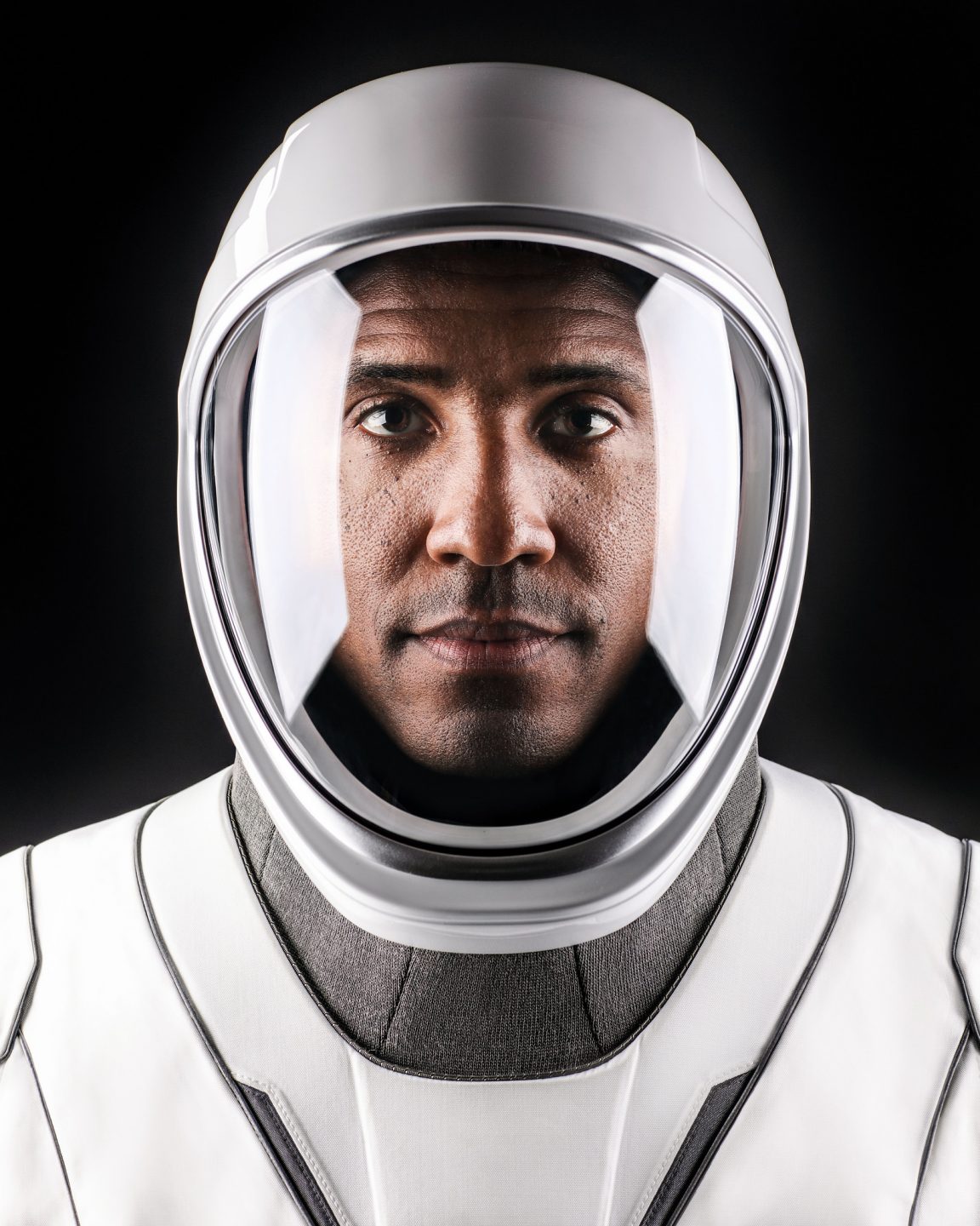 A man gazes into the camera in a sleek, futuristic-looking helmet and suit.