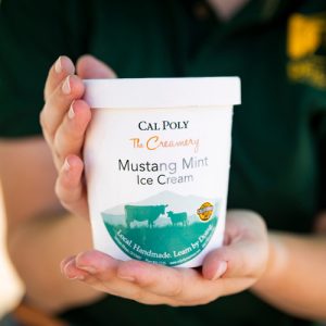 A person holds a pint of Cal Poly mint ice cream