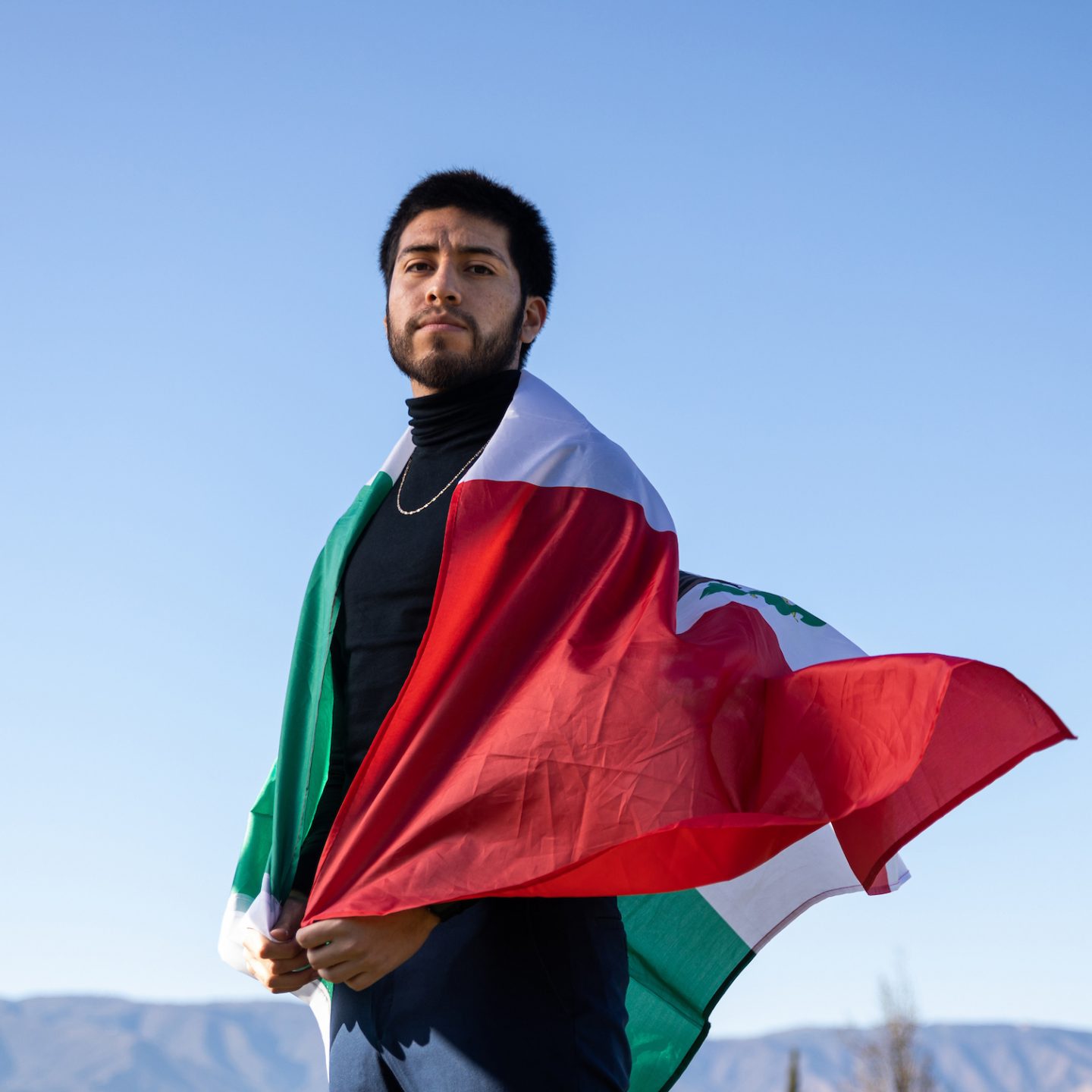 A man stands draped in the Mexican flag