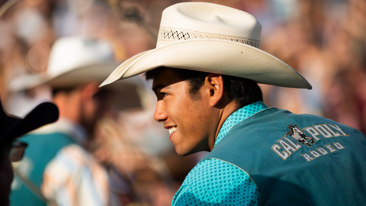 A student in a Cal Poly Rodeo vest and hat 