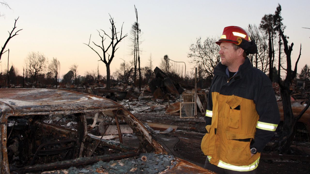 A firefighter in uniform looks over a burn area