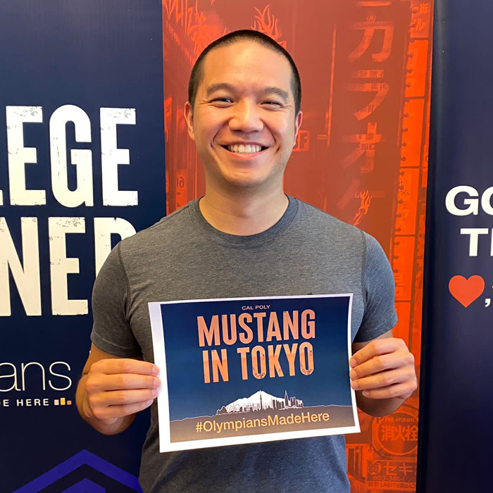 Nate Ngo holds a sign that says 'Mustangs in Tokyo'
