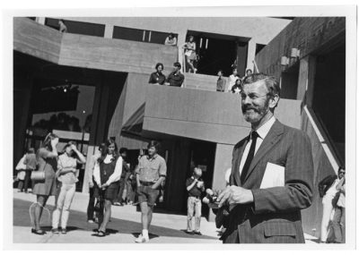A black-and-white archive photo of University Union architect Joseph Esherick smiling in the plaza