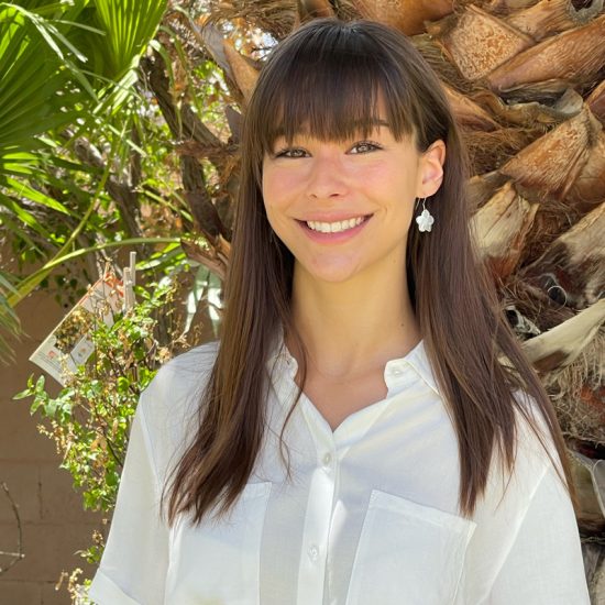 A head shot of Elise Fiskum smiline in front of a palm tree