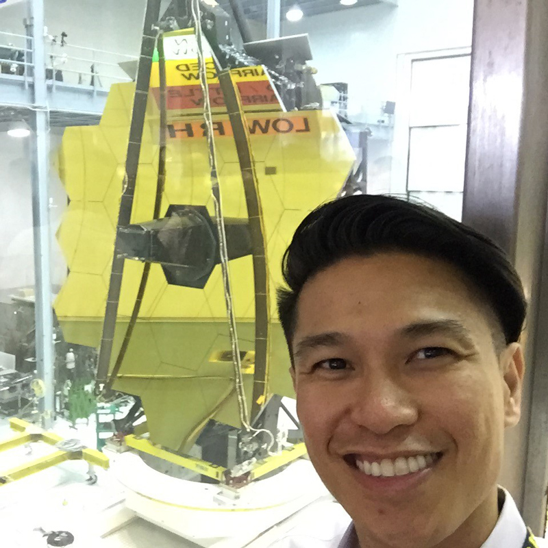 A man smiles in front of the James Webb telescope during construction