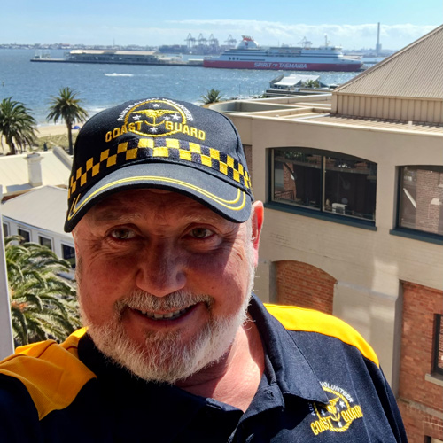 Kurt Irquhart wears a Coast Guard hat and shirt near a large port