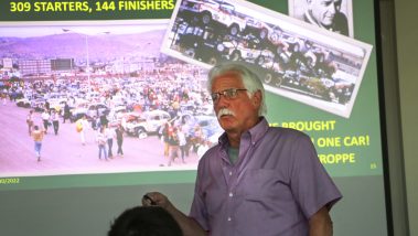 Roy Snover, member of the baja taxi team, speaks to students in front of a presentation slide about the Baja 500