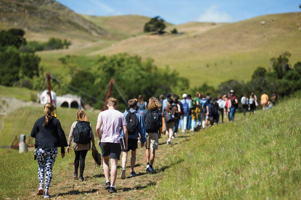 Dozens of students walk on a trail in Poly Canyon