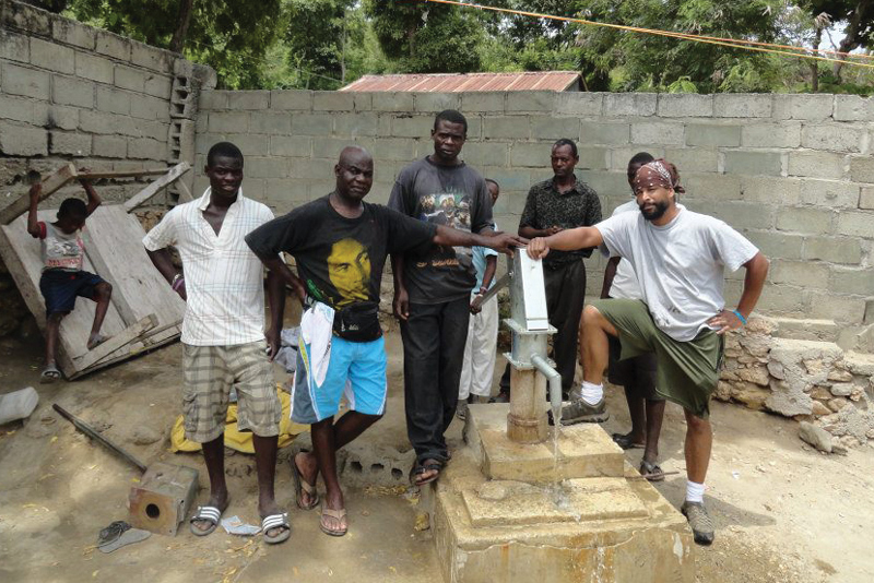 Five men stand near a water well in Haiti