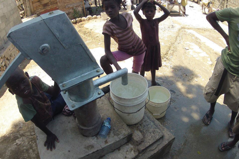 Three children in Haiti collect water from an upgraded well.