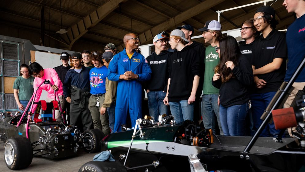 Victor Glover smiles while talking with the Cal Poly Racing team near their offroad and formula vehicles