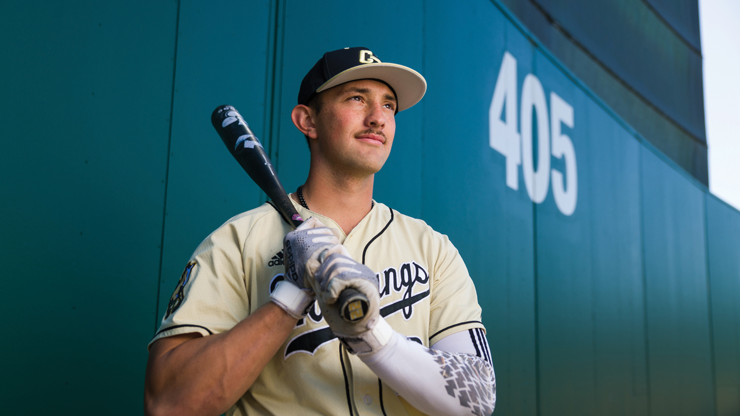 Brooks Lee holds a bat over his shoulder near the outfield fence at 405 feet at Baggett Stadium