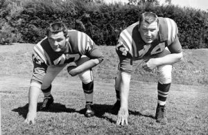 In black and white, two football players take a ready position