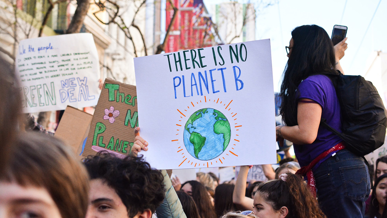 At a climate demonstration, a hand holds up a sign that says "There is no Planet B"