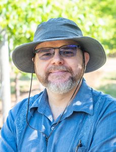 Matt Grieshop, in a collared shirt, glasses and wide brimmed hat