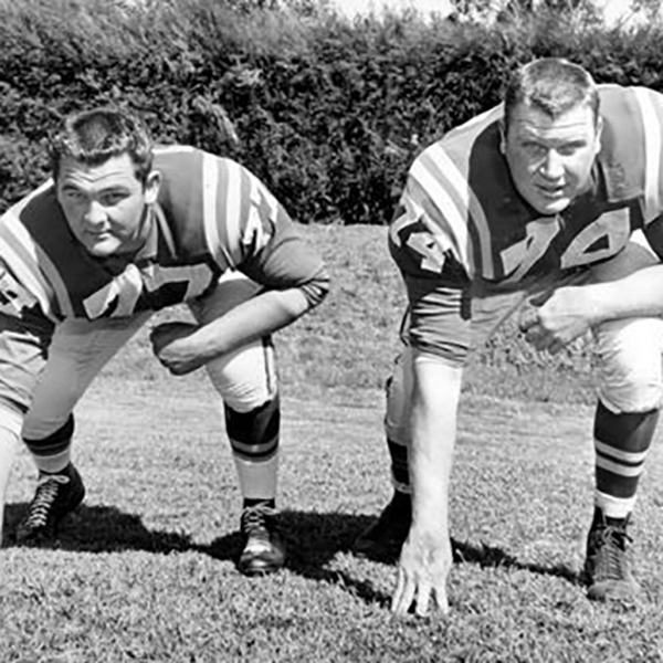 A young Madden in a football uniform lines up in three-point stance with a teammate