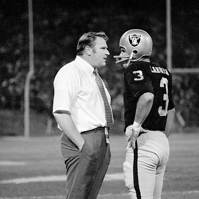 Madden speaks with a Raiders quarterback on the sidelines at a game
