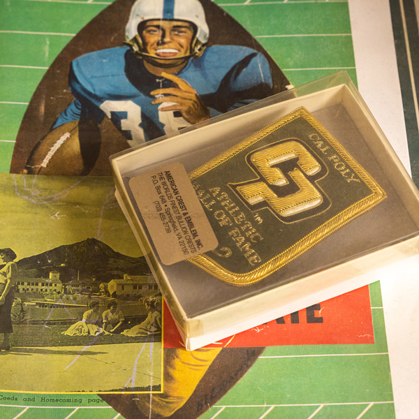 A Cal Poly Athletics hall of fame patch sits on a program and archive photo