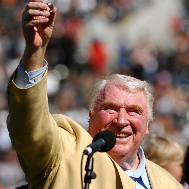 Madden, in a gold jacket, smiles as he holds up a ring in front of a crowd