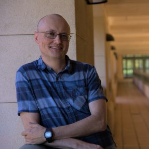 A man in a blue shirt leans against a wall at Orfalea College of Business