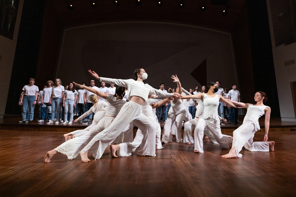 Dancers and singers dressed in white rehears on a wooden stage