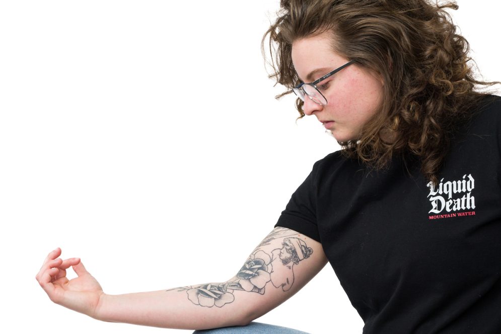A student wearing a black shirt displays a tattoo on their arm