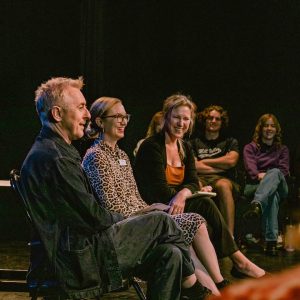 Actor Alan Cumming smiles while sitting with Cal Poly faculty in class