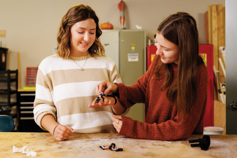 Two Cal Poly students test fit a prosthetic device in an engineering lab