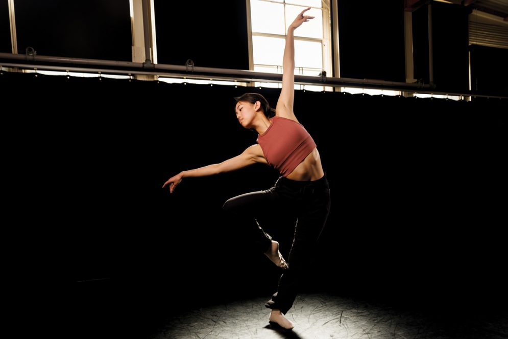 A Cal Poly student dancer strikes a pose in a rehearsal studio