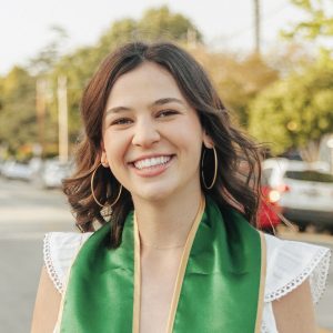 Peyton Ratto smiles wearing a green Cal Poly commencement stole