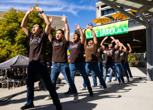A line of young men in matching "Lambda Theta Phi" t-shirts dance at the University Union