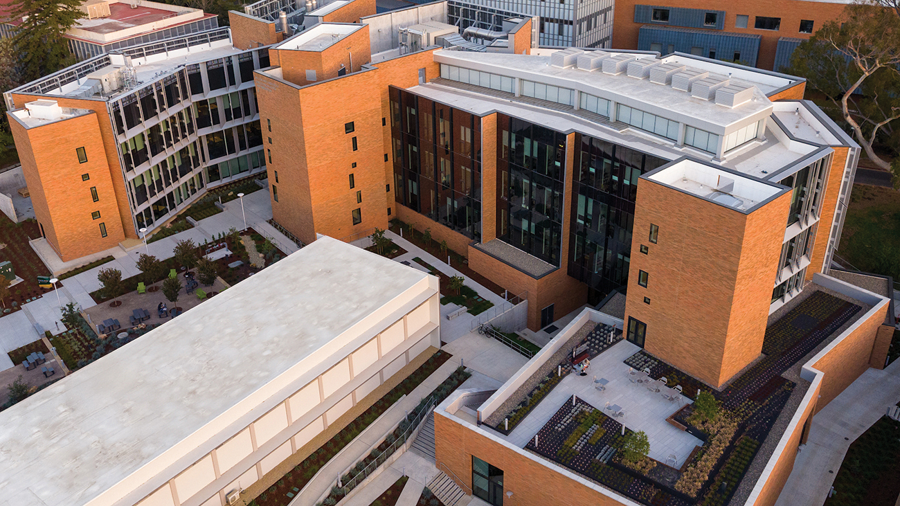 An aerial view of the Frost Center, a sprawling academic complex of red brick, glass and steel with a rooftop garden.